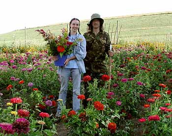 Two of MaryJanesFarm's employees pose for a photo in a field of flowers.